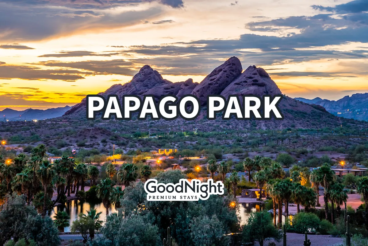 A tranquil view of Papago Park’s distinctive mountain formations, framed by palm trees with reflections glimmering in still water. The scene is serene, inviting, and distinctly Southwestern.