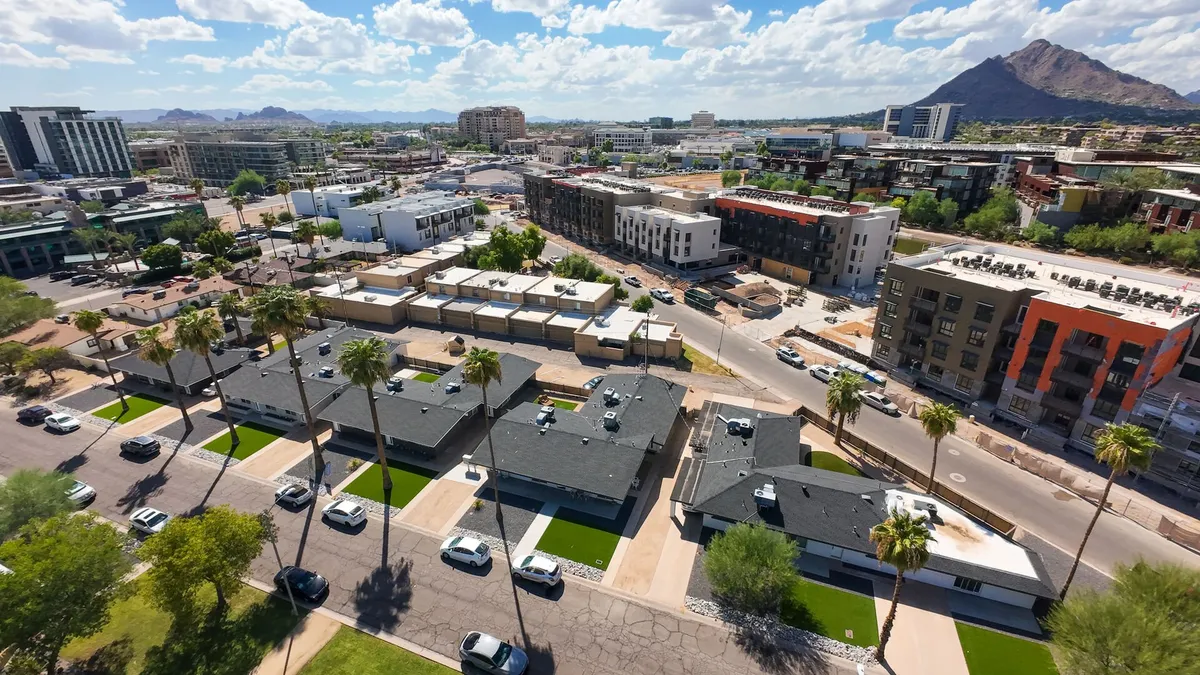 A bustling exterior streetscape featuring palm trees, modern buildings, and the lively backdrop of cars and people enjoying the area. The image captures the energetic, community-focused feel of Old Town Scottsdale and hints at the walkable, social environment described in the section.