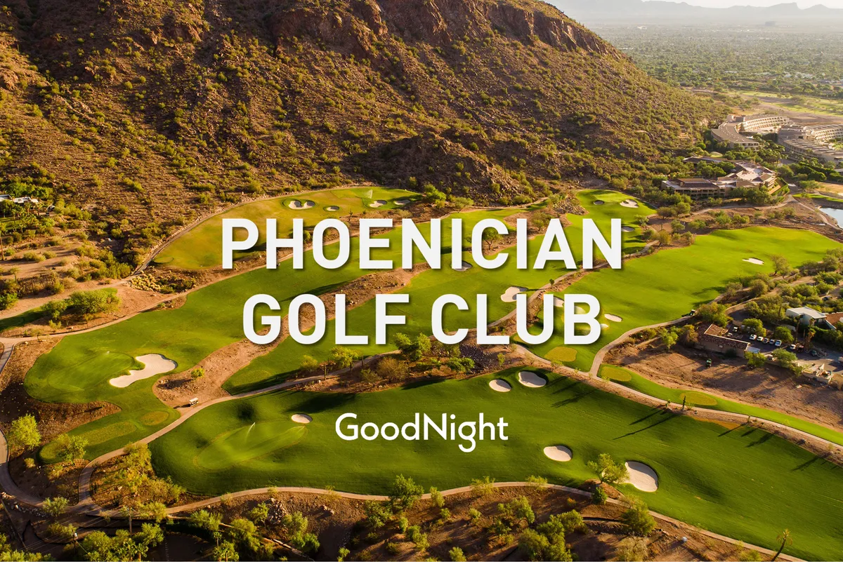 A wide exterior shot of manicured golf greens stretching out toward a dramatic mountain backdrop. The landscape showcases the open sky, neatly maintained fairways, and the serene natural environment surrounding the course.