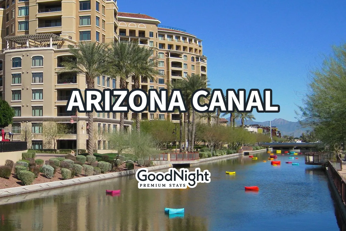 A bright, scenic view of the Arizona Canal features colorful boats, palm trees, luxury apartments, and walking paths. The canal is vibrant, inviting, and well-suited for family strolls, picnics, and outdoor fun.
